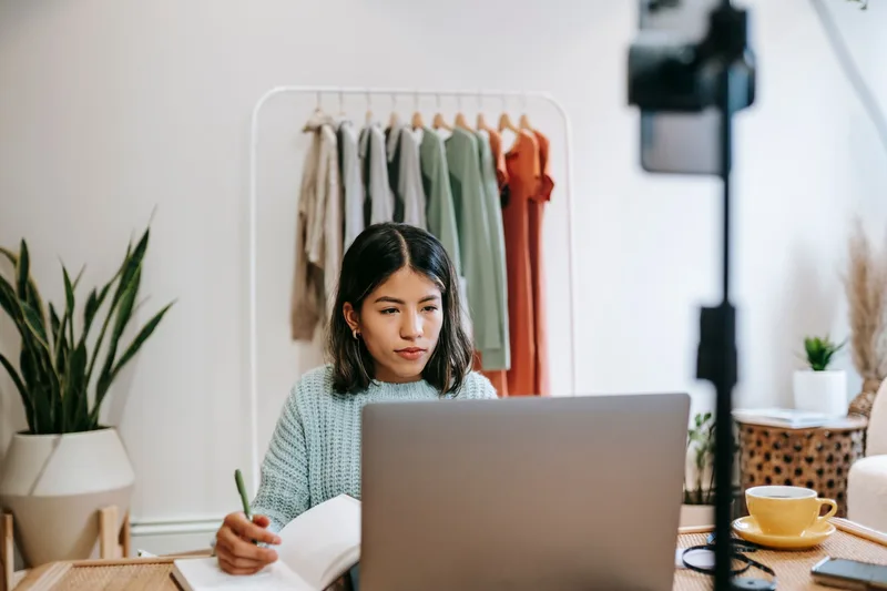 Content creator working at a desk with a notebook and laptop, planning a newsletter strategy