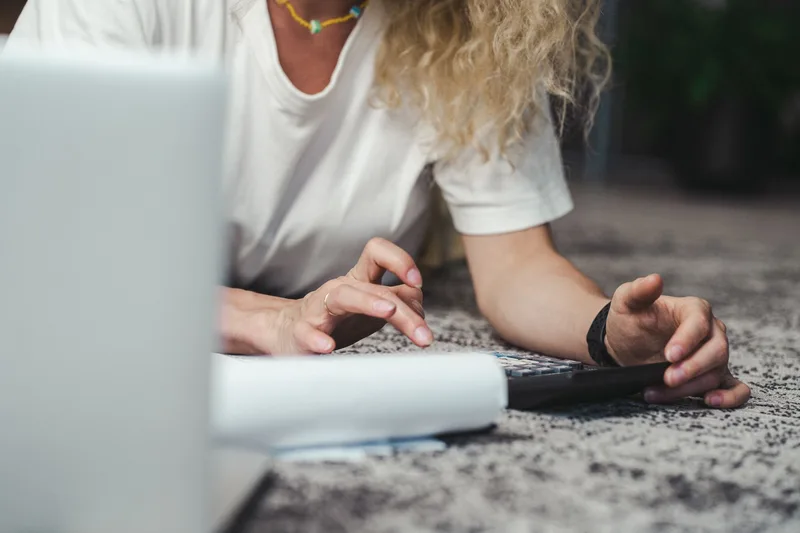 Person doing budget planning with a calculator and laptop