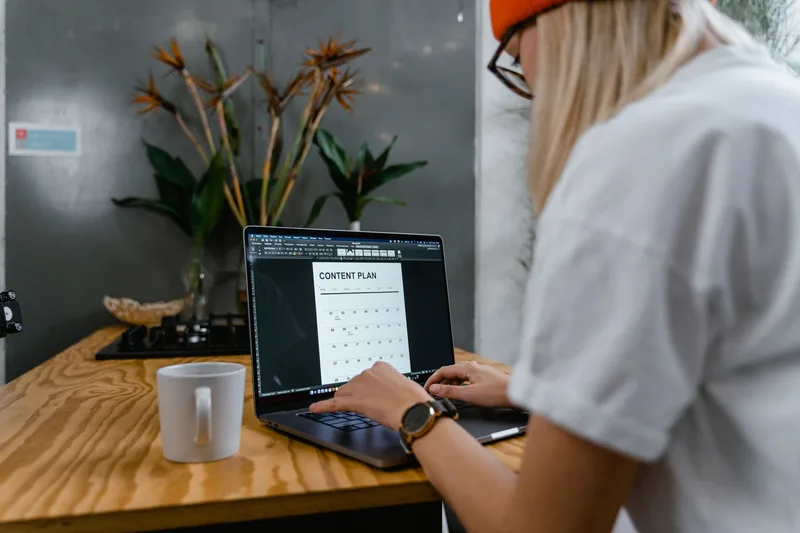 Creator working at a laptop with a content calendar, mapping out a scheduling strategy for social media posting across multiple platforms