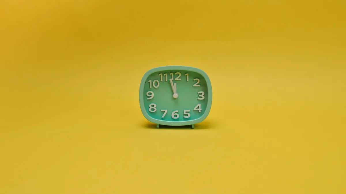 Analog clock on yellow background representing the importance of timing decisions for social media creators