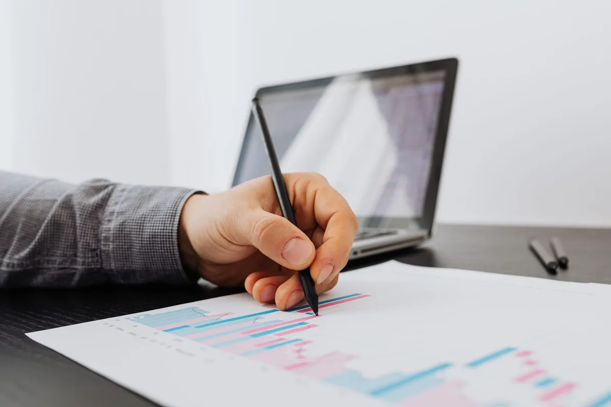 Creator at a laptop taking notes on a printed growth chart