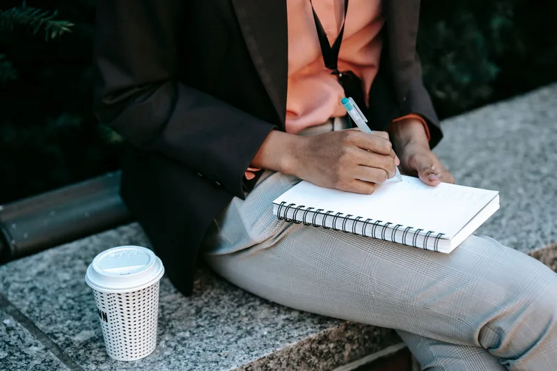 Creator sitting cross-legged journaling next to a cup of coffee