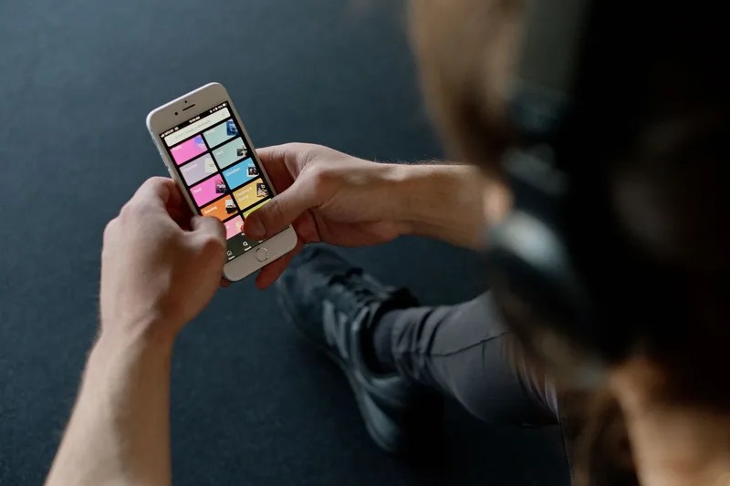 Person holding a smartphone listening to music with earbuds from a streaming playlist app