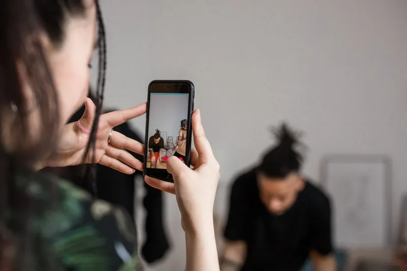 Person holding a smartphone and recording video content indoors in a home studio creative setup