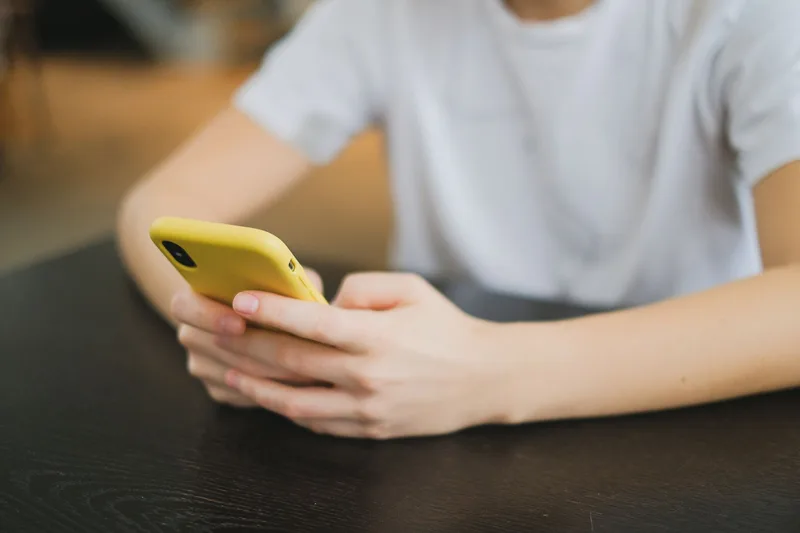 Person holding smartphone and engaging with social media content, representing active Twitter engagement