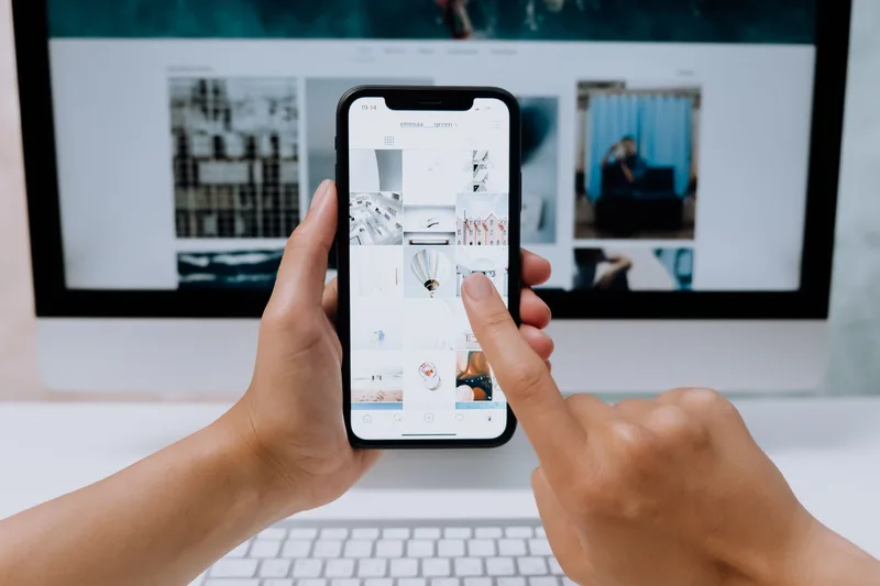 Hands scrolling through a grid of photo thumbnails on a smartphone app