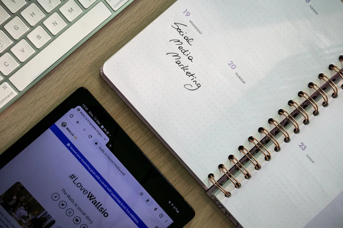 Top view of a notebook, tablet, and keyboard set up for social media content planning