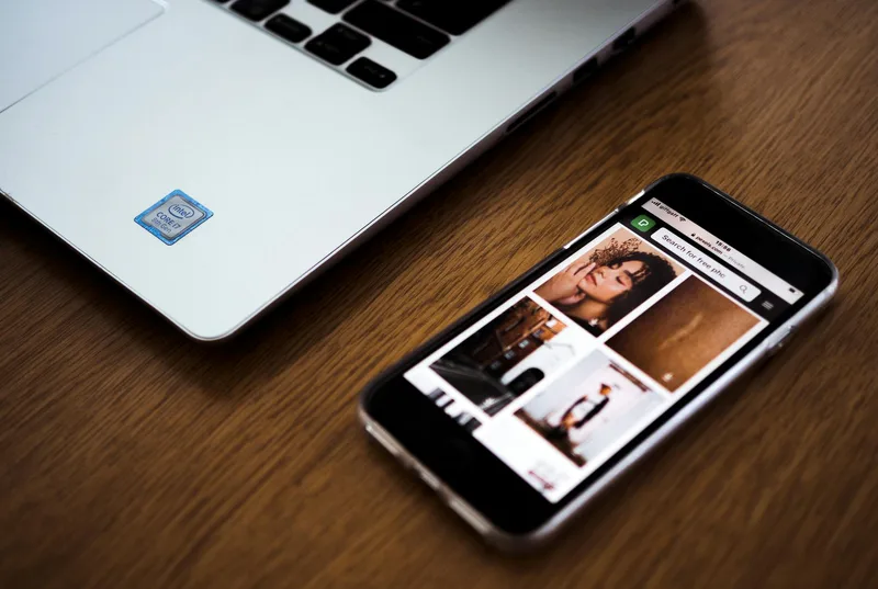 Smartphone next to a laptop on desk, representing LinkedIn’s mobile and desktop newsletter experience