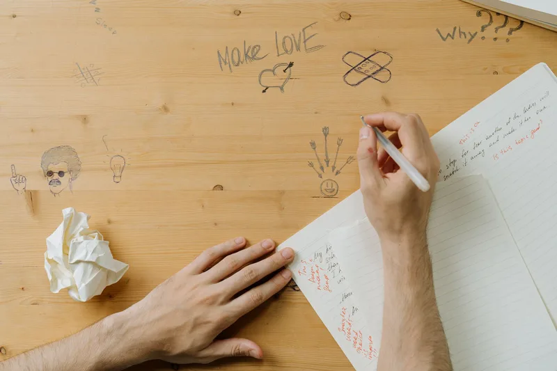 Creator sitting at a desk writing Twitter content ideas in a notebook, planning a thread strategy